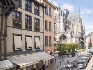 una calle de la ciudad con coches estacionados junto a una catedral en White Croco - Confort & Central en Troyes