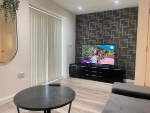 a living room with a table and a tv at Eaglet luxury home in Manchester
