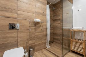 a bathroom with a shower with wooden walls and a toilet at Vlevo Dole Apartmán 3 in Rokytnice nad Jizerou