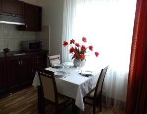 uma mesa de jantar com um vaso de flores em Chalet Villa REX em Druskininkai