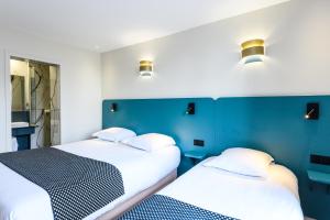 パリにあるホテル ダルザスの青い壁と照明が備わる客室で、ベッド2台が備わります。