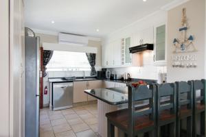 a kitchen with white cabinets and a stainless steel refrigerator at At 4 Umzumbe Beach Apartment, Mangrove Beach Estate in Melville