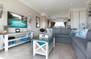 a living room with a couch and a tv at At 4 Umzumbe Beach Apartment, Mangrove Beach Estate in Melville
