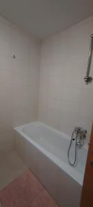 a white bath tub in a white tiled bathroom at Apartman Fran in Zagreb