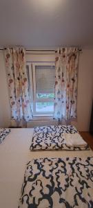 a bedroom with a bed and a window with curtains at Apartman Fran in Zagreb