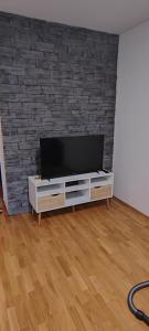 a flat screen tv on a stand in a room with a brick wall at Apartman Fran in Zagreb