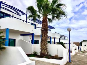 una palmera frente a un edificio blanco en Villa Pura Vida, en Playa Blanca