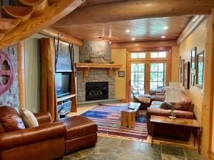 a living room with leather furniture and a stone fireplace at Cayuga Lodge South in Cooperstown