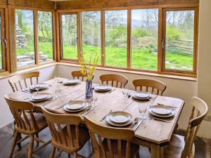 comedor con mesa, sillas y ventanas en Saul Hill, en Lake District National Park