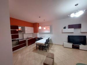 a kitchen with a table and chairs and a television at Redsun City Center Apartment in Vlorë