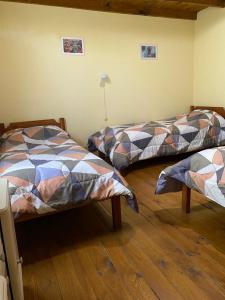 2 camas en una habitación con suelo de madera en Departamentos Ailen en Esquel