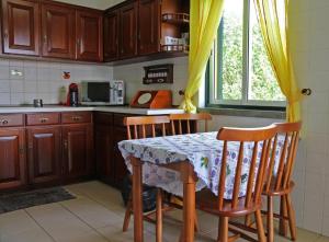 a kitchen with a table with chairs and a microwave at Casas da Boa Vista in Horta