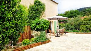 a patio with an umbrella and a table and chairs at Home Sweet AUM in Tourrettes-sur-Loup