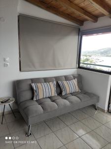 un sofá gris en una habitación con una pantalla grande en Vetti Rooms, en Skiathos