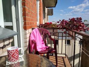 uma cadeira rosa sentada numa varanda com uma mesa em Brīvdienu dzīvoklis em Madona