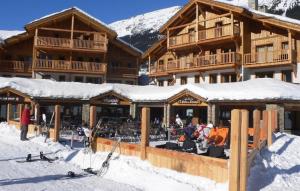 a group of people standing in the snow in front of a ski lodge at L’Aster in Lanslebourg-Mont-Cenis