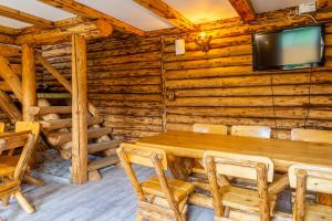una sala da pranzo con tavolo e TV in una baita di tronchi di Vila Rustica a Moieciu de Sus