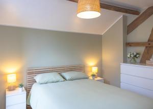 a bedroom with a white bed and two night stands at Gîte Le Haut des Vannes in Neufchâteau