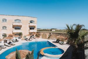 a hotel with a swimming pool in front of a building at Ogygia Suites Gozo in Għarb