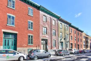 un grupo de coches estacionados frente a un gran edificio de ladrillo en Apartment et Studio montreal en Montreal