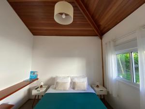um quarto com uma cama azul e um tecto de madeira em Ao Mar - Hospedagem em São Sebastião