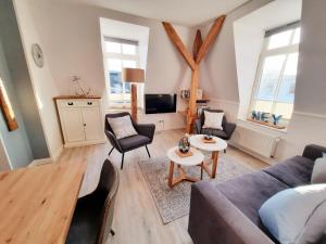 a living room with a couch and chairs and a tv at Villa Liewald - Wohnung Inselflair in Norderney