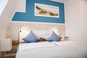 a bedroom with a white bed with blue walls at Villa Liewald - Wohnung Inselflair in Norderney