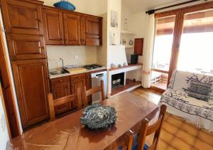 a kitchen with wooden cabinets and a table and a chair at Villetta Elisa Best Vacation Ever Sant'Elmo in Costa Rei