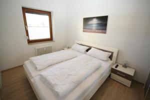 un letto bianco in una stanza con finestra di Haus Belvedere App 12 WLAN inkl a Grömitz