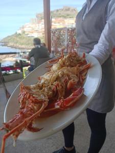 a woman holding a plate of lobsters on a plate at Antica Pensione Pinna in Castelsardo