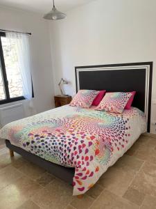 - une chambre avec un lit doté d'une couette et d'oreillers colorés dans l'établissement gîte de Jo et Chantal, à Belgentier