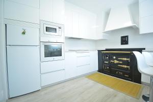 a kitchen with white cabinets and a black appliance at GALIHOST - A Casa do Olivo in Meis