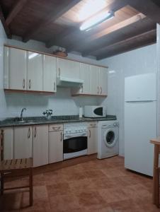 eine Küche mit weißen Schränken und einem weißen Kühlschrank in der Unterkunft Casa Villastur in Covadonga