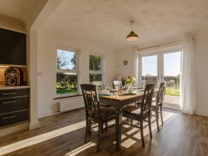 a dining room with a table and chairs and a television at Highgrove in Gissing