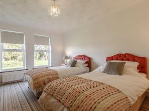 two beds in a bedroom with two windows at Highgrove in Gissing