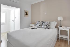 a white bedroom with a large white bed with pillows at Modern 2 Bedroom Apartment in Estrela with Outside Terrace! Amazing for Families, Couples, Friends in Lisbon