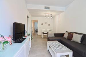 ein Wohnzimmer mit einem Sofa und einem Flachbild-TV in der Unterkunft Apartamento San Leonardo Playa (Free Parking) in Cádiz