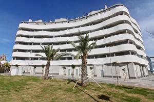 ein weißes Gebäude mit Palmen davor in der Unterkunft Apartamento San Leonardo Playa (Free Parking) in Cádiz