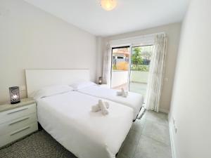 a white bedroom with two beds and a window at Apartment in Marbella Center with private parking in Marbella