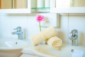 un lavandino in bagno con asciugamano e un fiore sopra di Apartment Speiereckblick a Mauterndorf