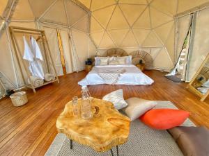 a room with a bed and a table in a tent at Bohemia Glamping 