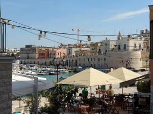 a group of tables with umbrellas and boats in a harbor at L'Ancora in Bisceglie