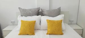 białe łóżko z trzema żółtymi poduszkami w obiekcie Aqua Magic Lake On Luminita Studio w Mamai