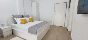 biała sypialnia z dużym białym łóżkiem z żółtymi poduszkami w obiekcie Aqua Magic Lake On Luminita Studio w Mamai
