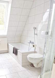 a white bathroom with a toilet and a tub at Paulchens Kajüte in Glücksburg