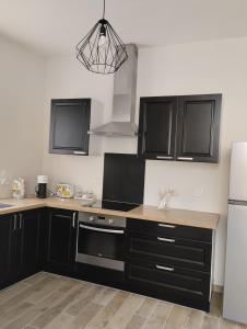 - une cuisine avec des armoires noires et un réfrigérateur blanc dans l'établissement Au cocon Chapellois, à La Chapelle-Saint-Mesmin