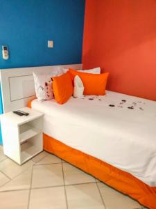 a bed with orange and white pillows and a table at Kadavu Accommodations in Maun
