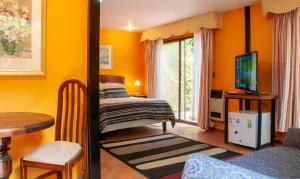 1 dormitorio con paredes de color naranja, 1 cama y 1 mesa en Hostería y Spa Llano Real, en Olmué