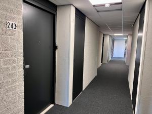 un couloir d'un immeuble de bureaux avec des portes noires dans l'établissement eindhovenapart, à Eindhoven