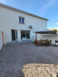 un patio con mesa y sombrilla en Maison Confort et détente, en Tavaco